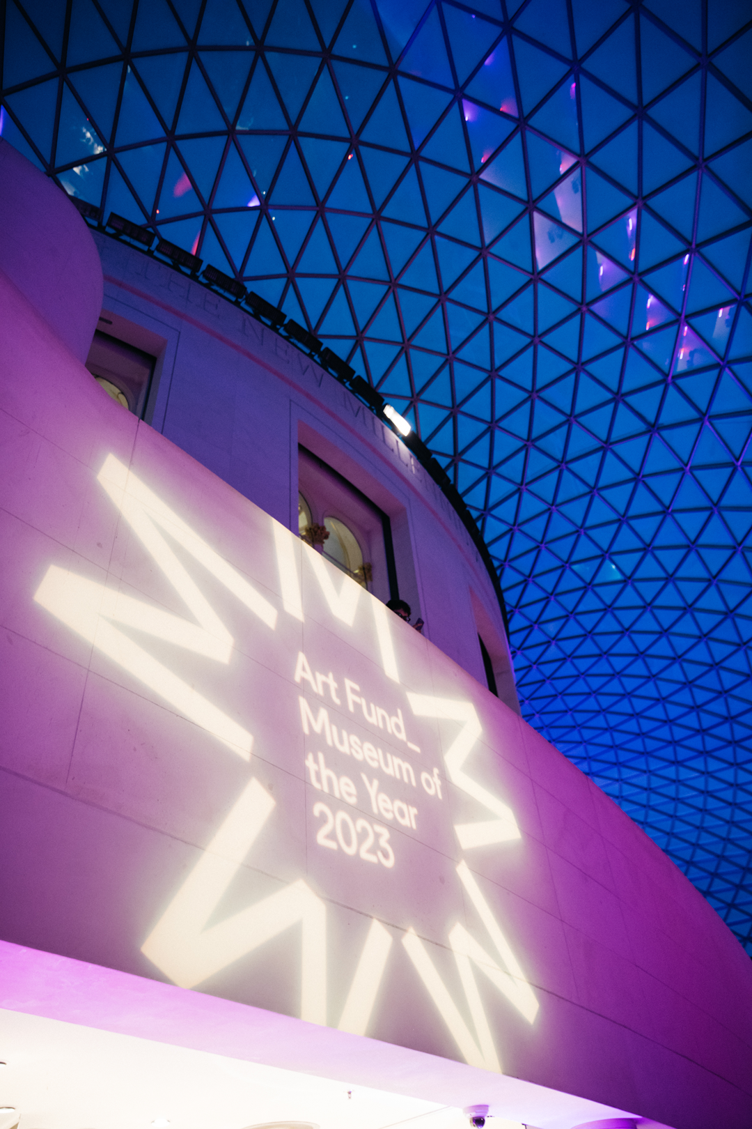 The Museum of the Year 2023 starburst projected in light across the British Museum Great Court wall.